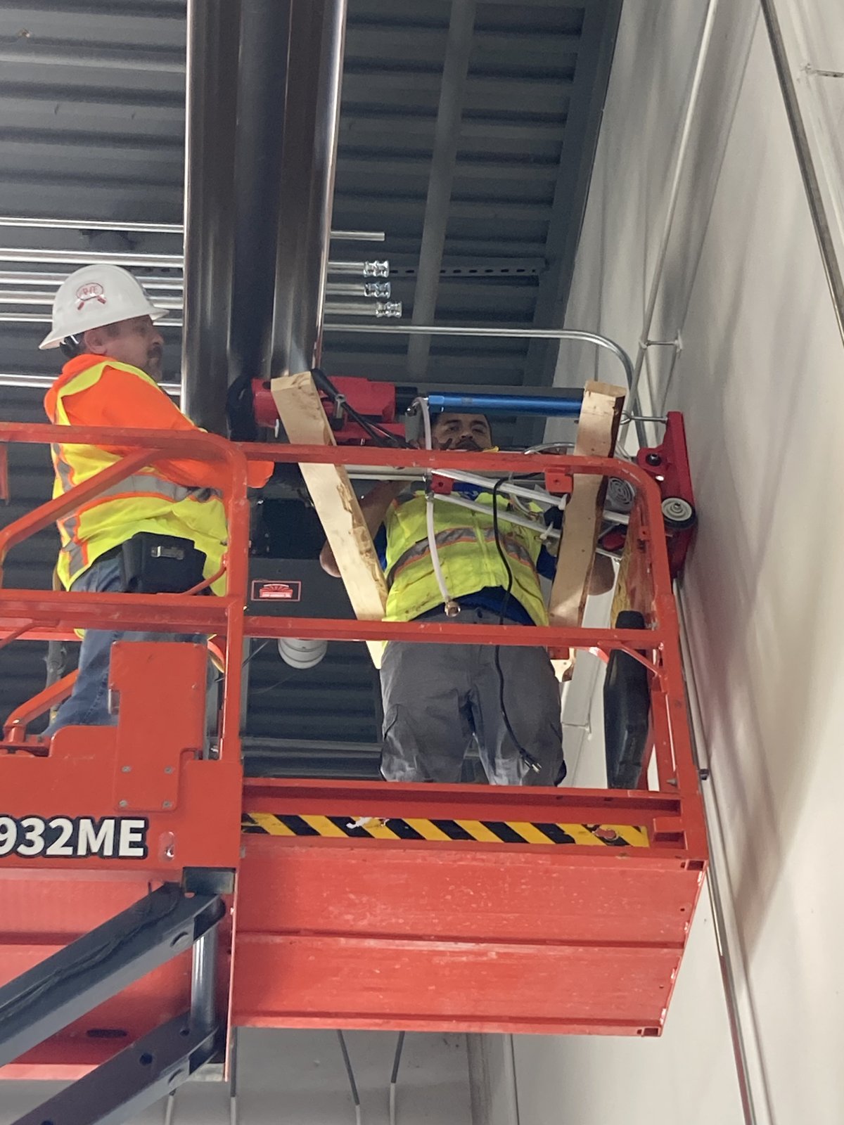 A.H. Electrical electricians installing conduit from a scissor lift in a commercial building